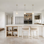 Caesarstone 5144 Rossa Nova surfaces in Modern kitchen with island, two stools, pendant lights, wooden cabinetry, stainless appliances, and large window.